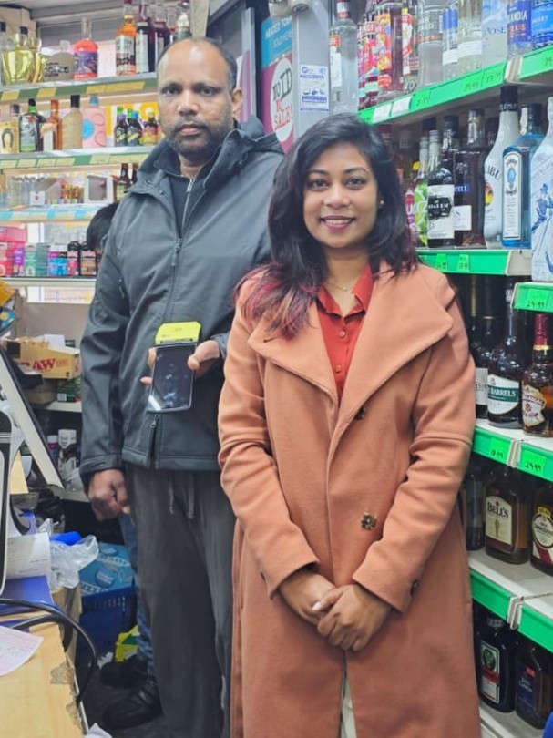 Happy with the owner of an independent off-licence, new card terminal in hand